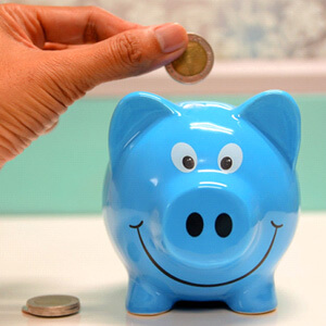 hand putting coin in blue piggy bank
