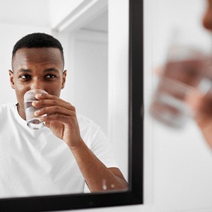 a man looking in a mirror and holding a cup of water