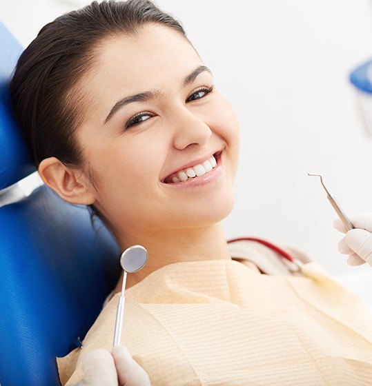 Woman in dental chair smiling during exam