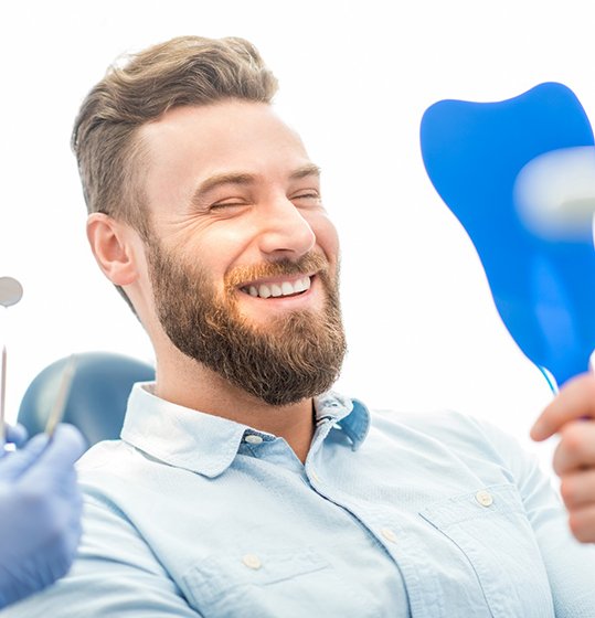 Man admiring his smile after dental bonding in Denison