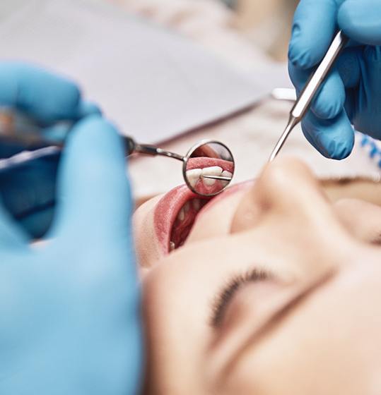 Closeup of Denison orthodontist inspecting patient’s teeth