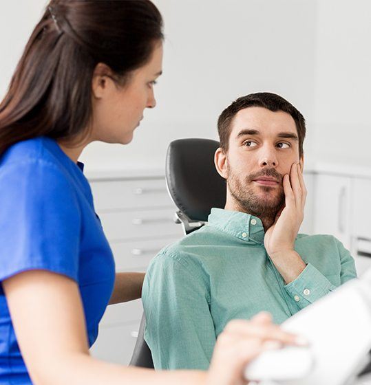 Man hold cheek during restorative dentistry appointment