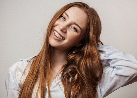 smiling young woman with clear/ceramic braces in Denison