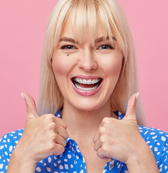 excited woman giving thumbs up for clear braces