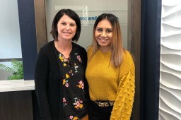 Dental team member and patient smiling together in entry way