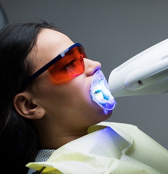 Woman receiving teeth whitening in office