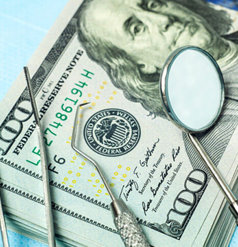 dental instrument on stack of $100 bills