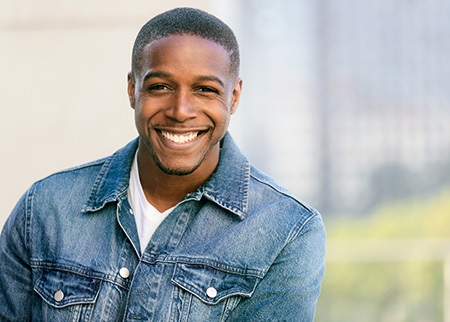 Man in denim jacket outside and smiling