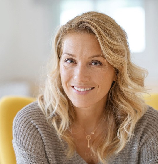 Woman in grey sweater smiling at home