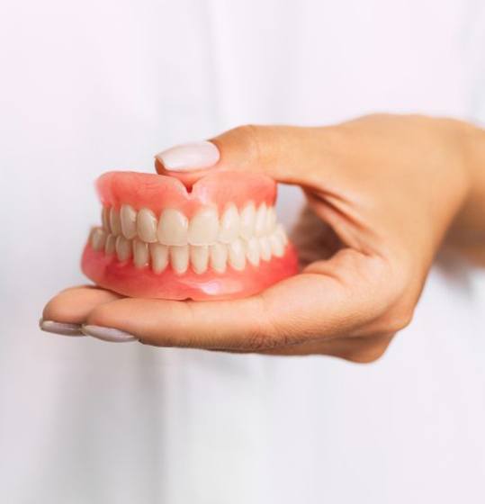dentist holding set of full dentures
