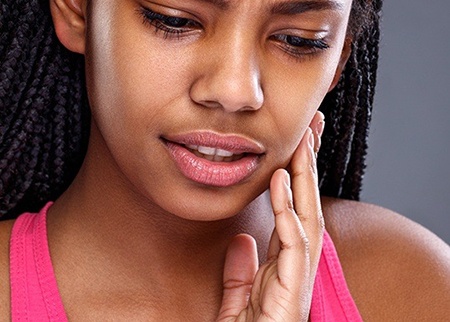 Woman in need of emergency dentistry holding jaw