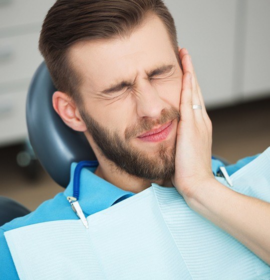 Man holding cheek during emergency dentistry visit