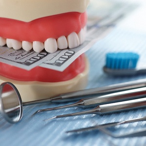 dental instruments with money, showing that taking care of your smile saves money