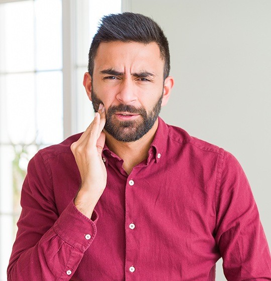 Man in need of tooth extraction holding jaw