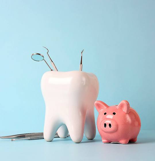 A large model tooth sitting next to a piggy bank