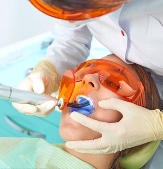 Dental team member using curing light to harden a filling