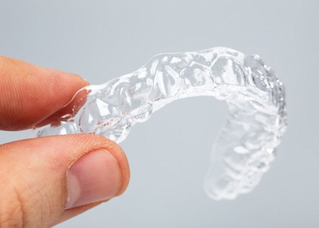 A person holding a clear aligner.