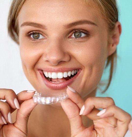 A woman holding a clear aligner.