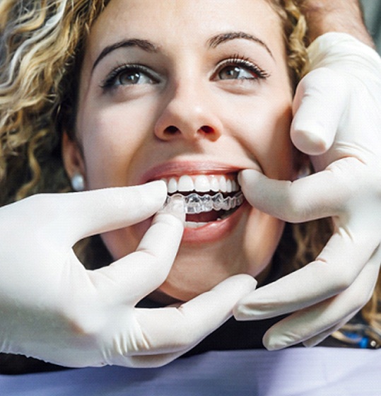 Dentist in Denison placing Invisalign aligners on patient
