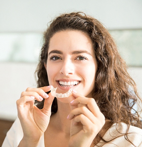 woman holding Invisalign aligner