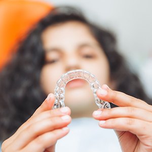 Teenager holding Invisalign aligner in treatment chair