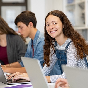 Teen girl smiling while working on computer in classroom