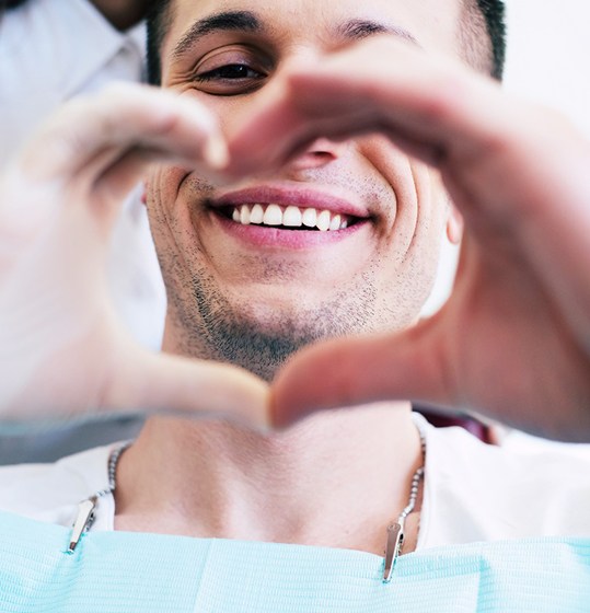 A dental patient making a heart symbol with his hands