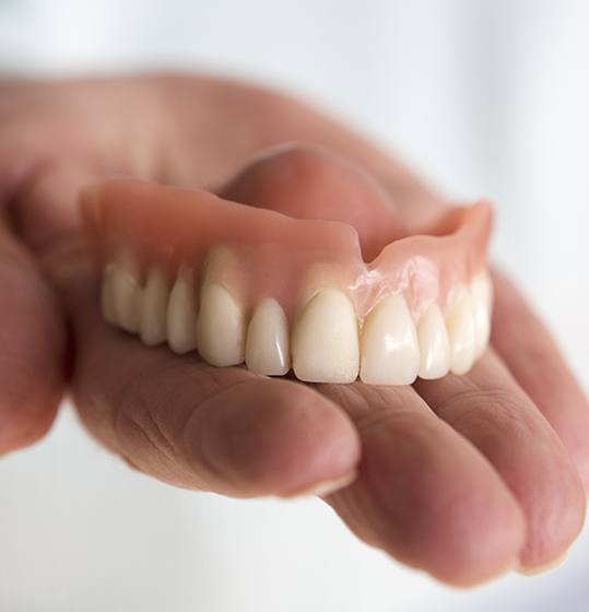 Hand holding a full denture