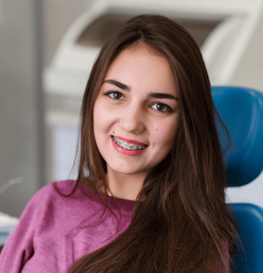 Young woman with braces in dental chair after orthodontic emergency care