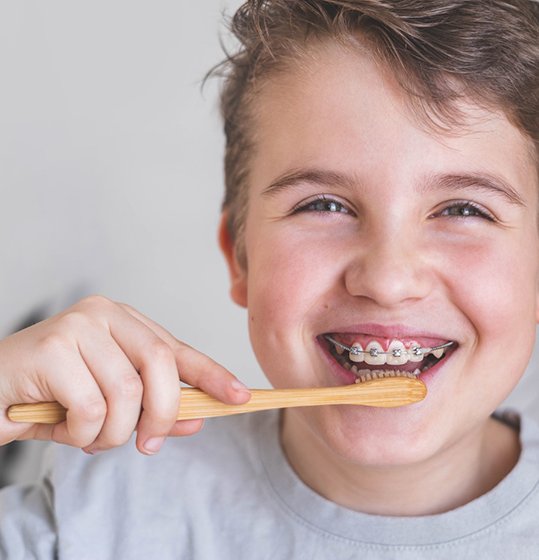 Boy with braces brushing his teeth