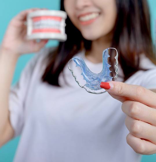 Young woman holding her retainer in foreground
