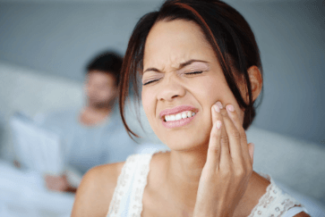 Woman in need of emergency dentistry holding cheek