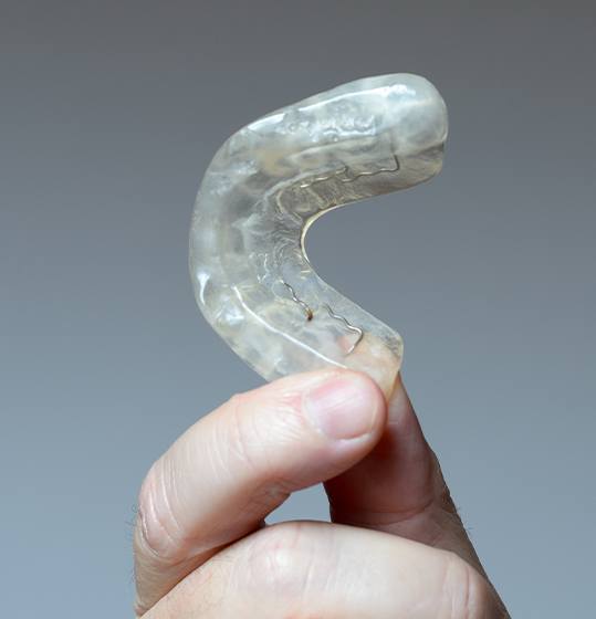 Hand holding an occlusal splint for TMJ therapy