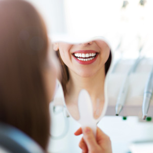 Patient looking at their smile in a dentist’s mirror