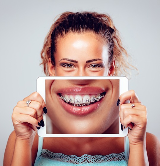Woman holding tablet, showing image of orthodontic braces