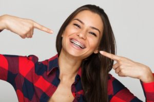 girl smiling and pointing to her braces