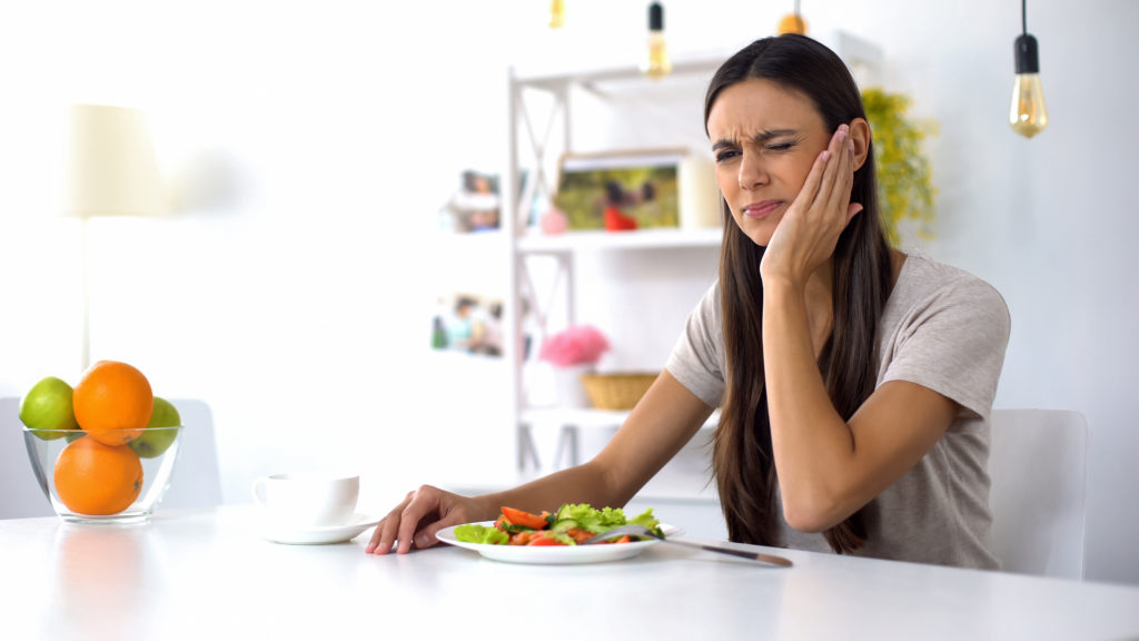 Woman experiencing tooth sensitivity while eating