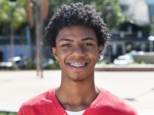 Young man with braces smiles before visiting Denison orthodontist 