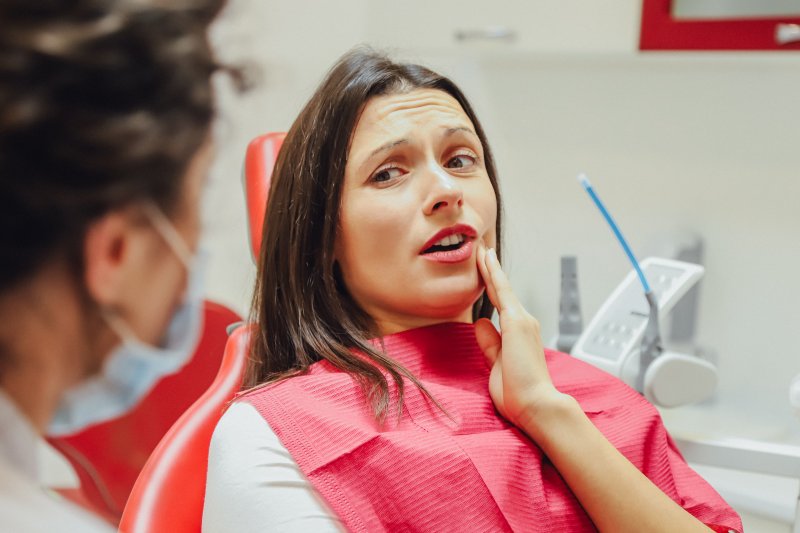 Woman holding cheek at dental office