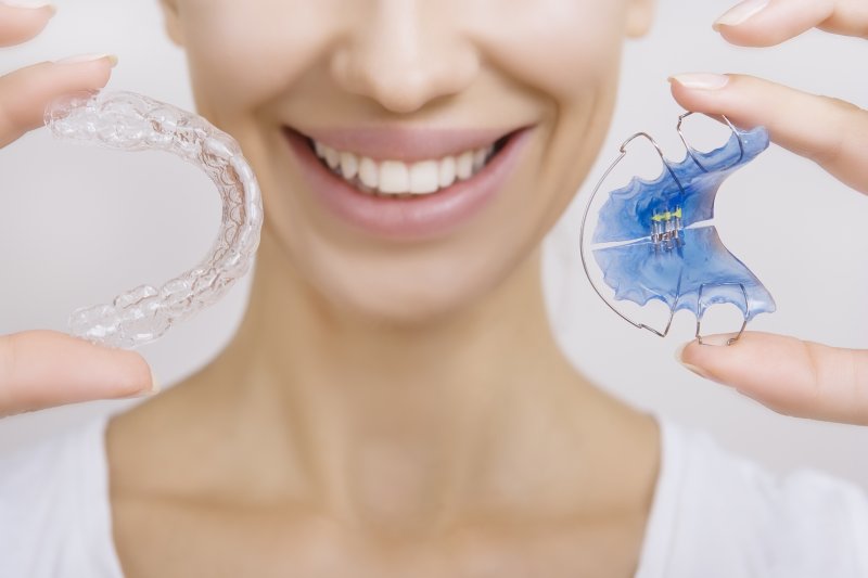 young girl holding Invisalign aligner and retainer