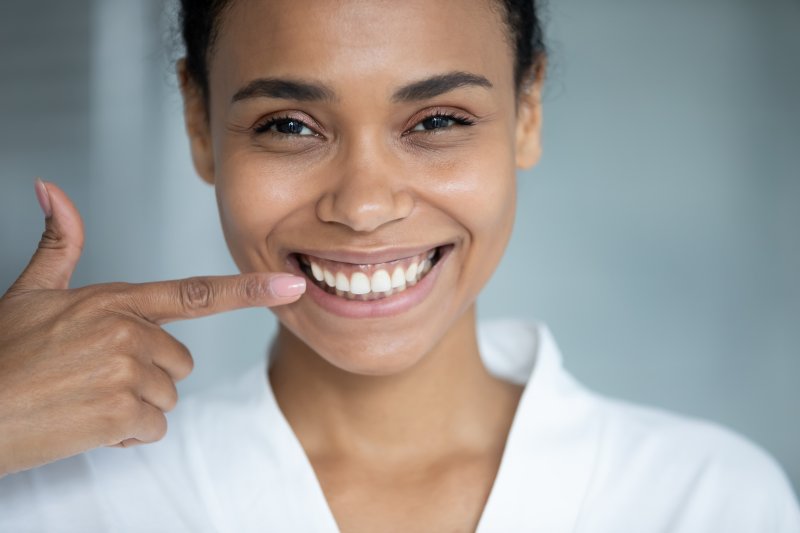 young woman pointing to straight teeth