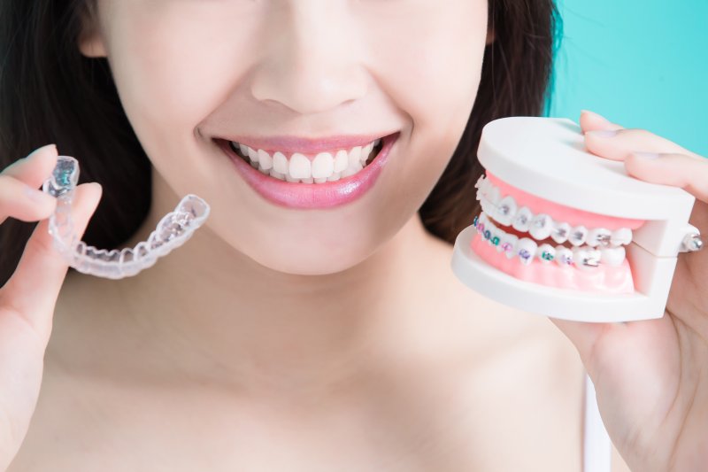 woman holding braces and Invisalign