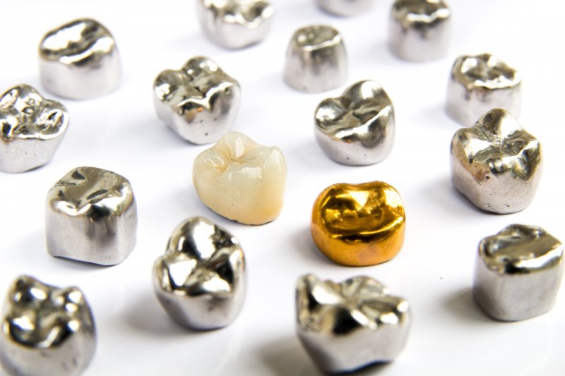 Various dental crowns of different colors (silver, natural, gold) splayed out side by side