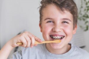 a young child with braces brushing his teeth